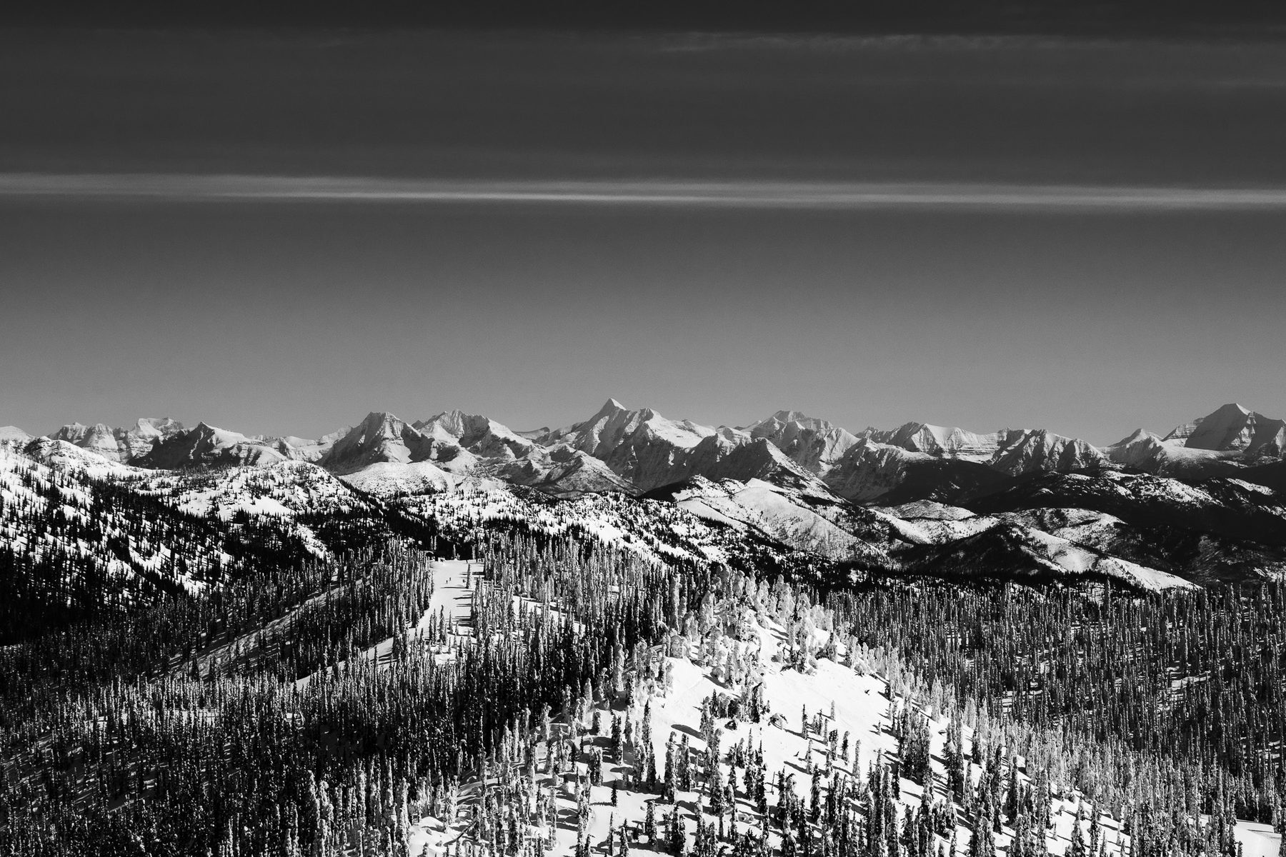 Black and white mountain range under winter cloud